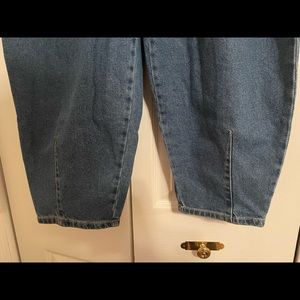 Blue denim jeans that have a flowy design and are somewhat sinched and pleated.